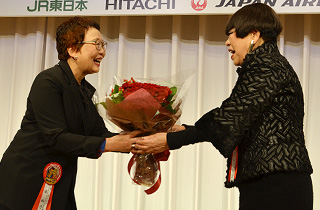 Presenting a flower bouquet to Mr. Koshino Junko who was honored as a cultural contributor